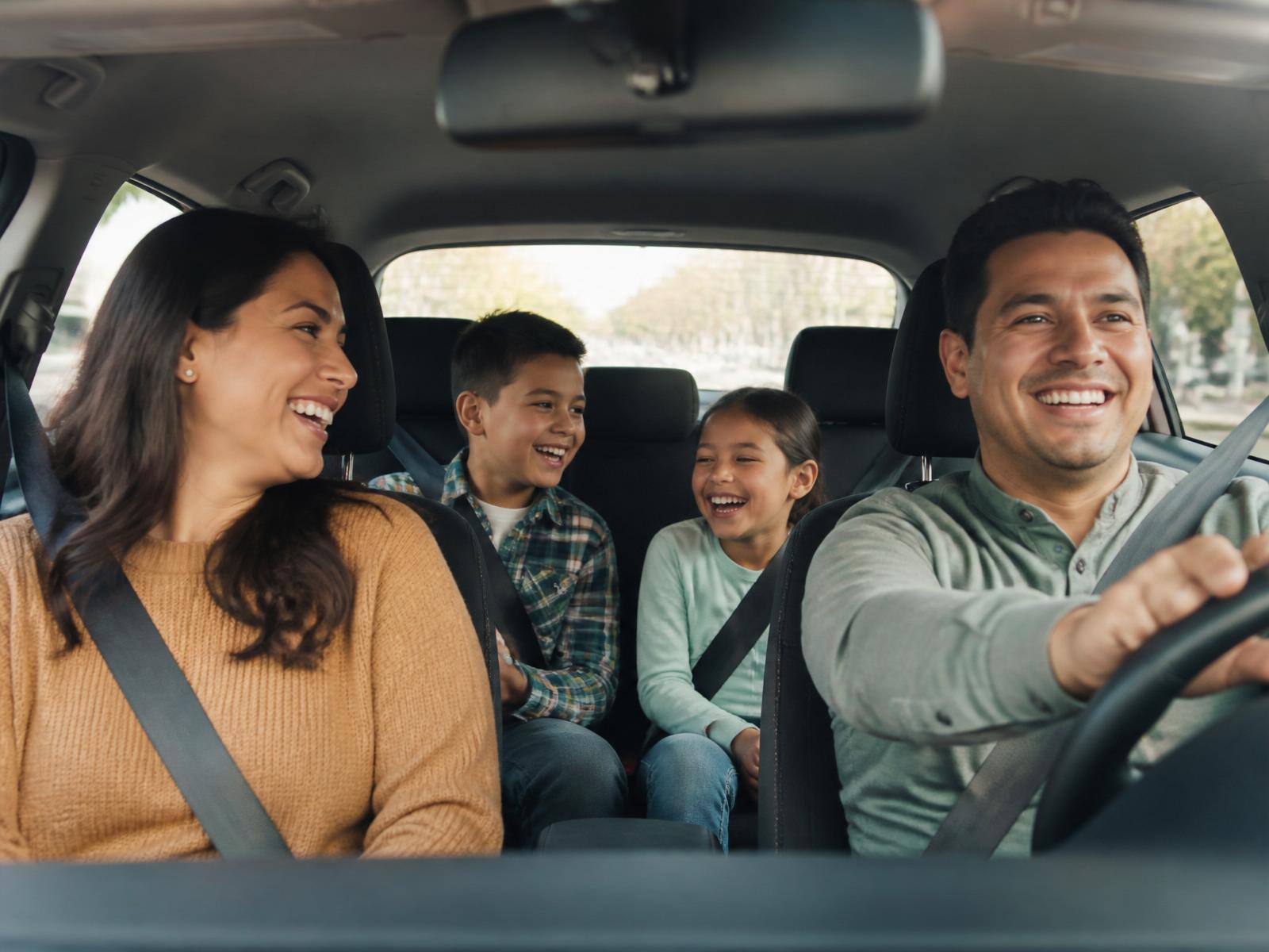 A parent and child laughing in the car while listening together